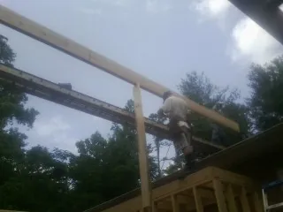 Carpenter setting a ridge beam over a new addition frame — Ice Dam Removal by Roofing Brothers in Pinewood