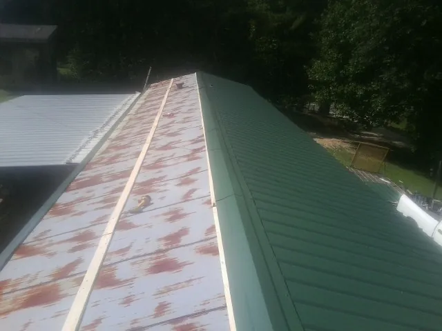 Old rusted panels beside newly installed green metal roofing — Wind Damage Roof Repair by Roofing Brothers in Pinewood