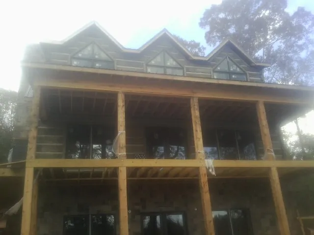 Dormers and porch framing on a large log home under construction — Roof Coating work by our crew in Pinewood