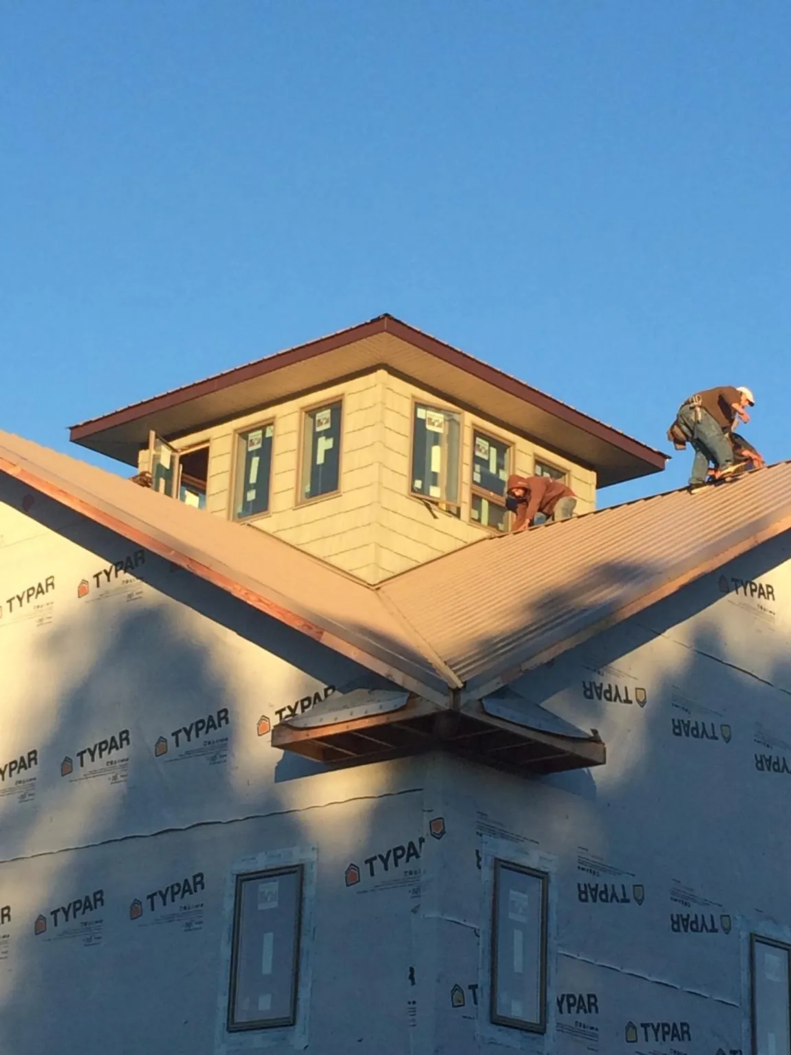 Roofers working around a rooftop cupola on a new metal roof at sunset — Roof Waterproofing in Pinewood by Roofing Brothers